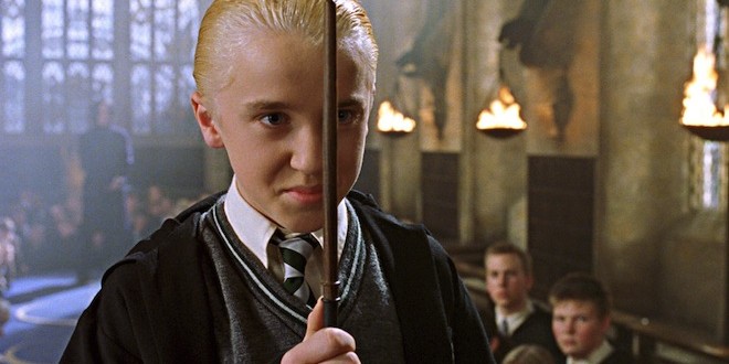 Draco with a hand in front of his face