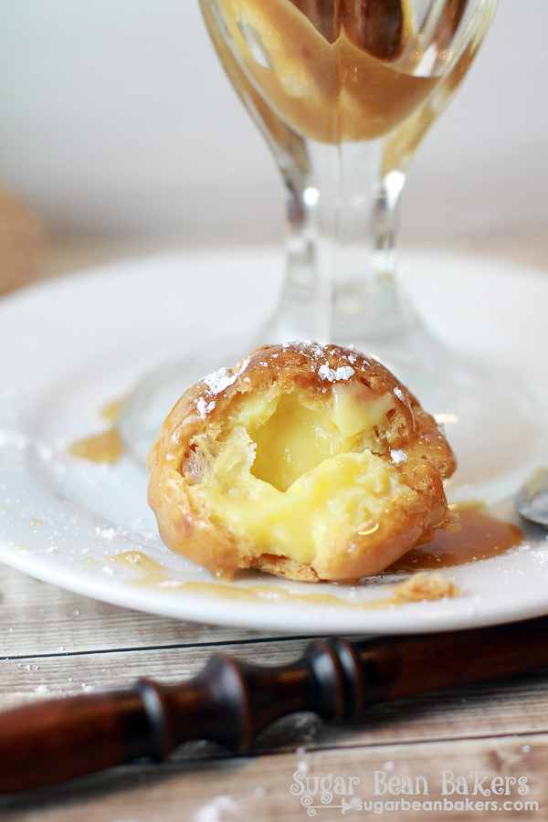 Close-up of a cream puff. Part of it has been either bit off or cut to expose the cream inside