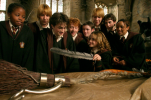 Gryffindors admiring Harry's new Firebolt and Hermione is holding a feather