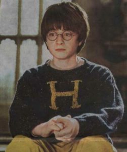 Harry wearing a Weasley sweater sitting down