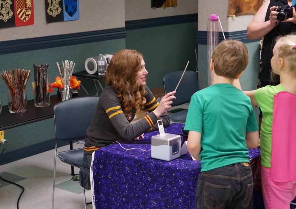 Hermione cosplayer and children testing free wands at library event