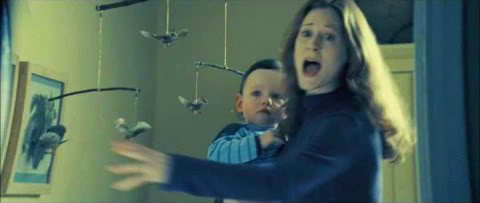 Lily Potter holds infant Harry Potter and looks terrified as Lord Voldemort enters Harry's nursery