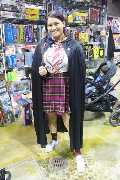 A cosplayer dons her Gryffindor costume in front of a vendor.