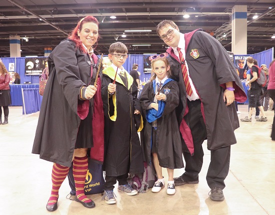 A family of four represents three Hogwarts houses wearing robes and waving wands.