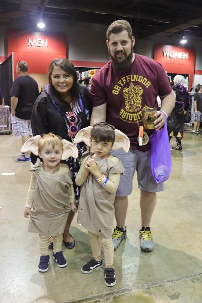 A family of four huddles together with the two children wearing house elf ears and potato sacks, and their mother wearing a Ravenclaw robe.