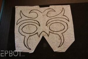 a piece of white tissue paper with a symmetrical swirling black pattern inked on it