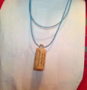 Display of a double-stranded necklace of small light blue beads with a cork pendant