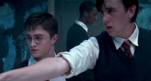 Neville pointing his wand with Harry at his side