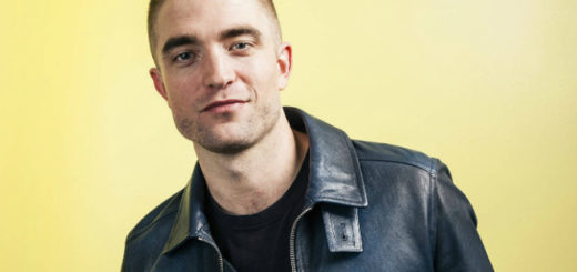 Robert Pattinson smiling in front of a yellow background