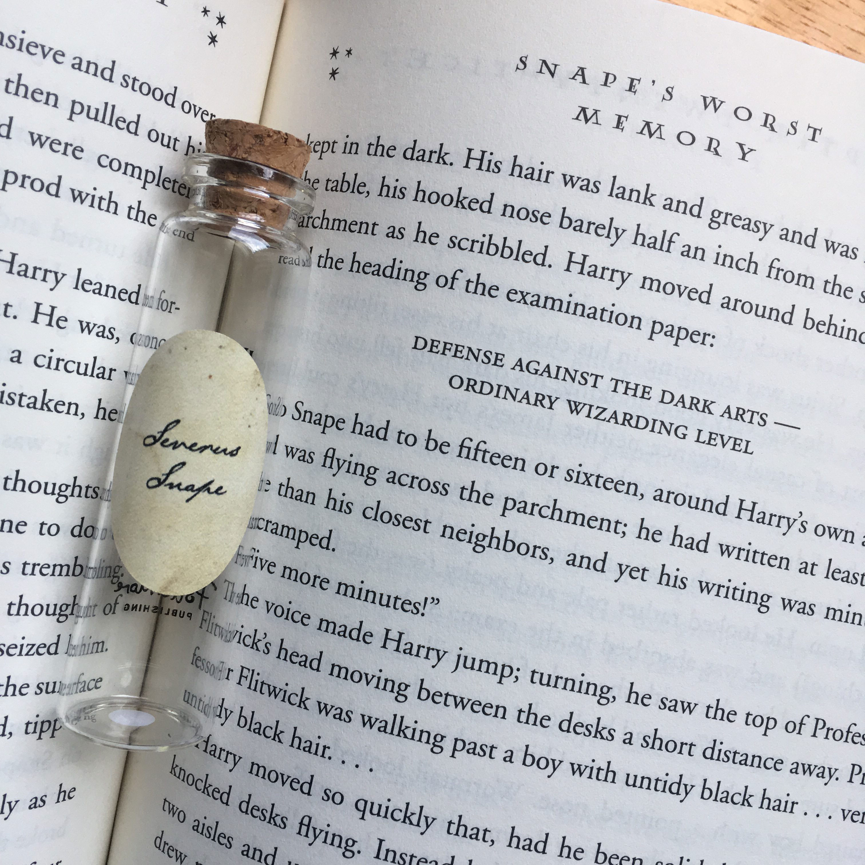 Severus Snape’s Pensieve vial lying on top of a page containing the memory of Snape taking the OWL for Defense Against the Dark Arts, from Chapter 28, “Snape’s Worst Memory,” in “Harry Potter and the Order of the Phoenix”