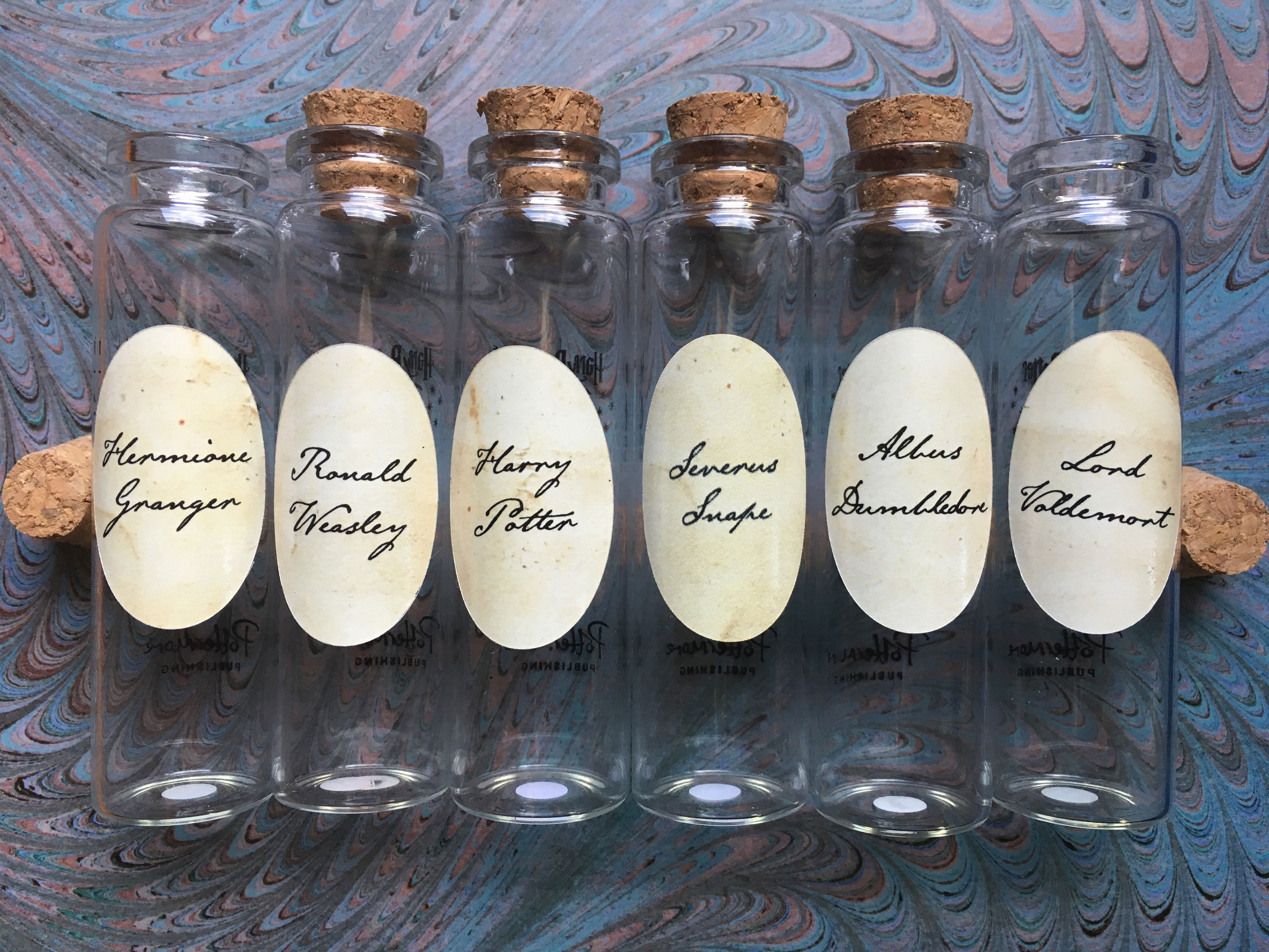 Pensieve vials with corks from Audible’s “A Harry Potter Pensieve Experience,” featuring iconic characters Albus Dumbledore, Severus Snape, Lord Voldemort, Harry Potter, Ronald Weasley, and Hermione Granger