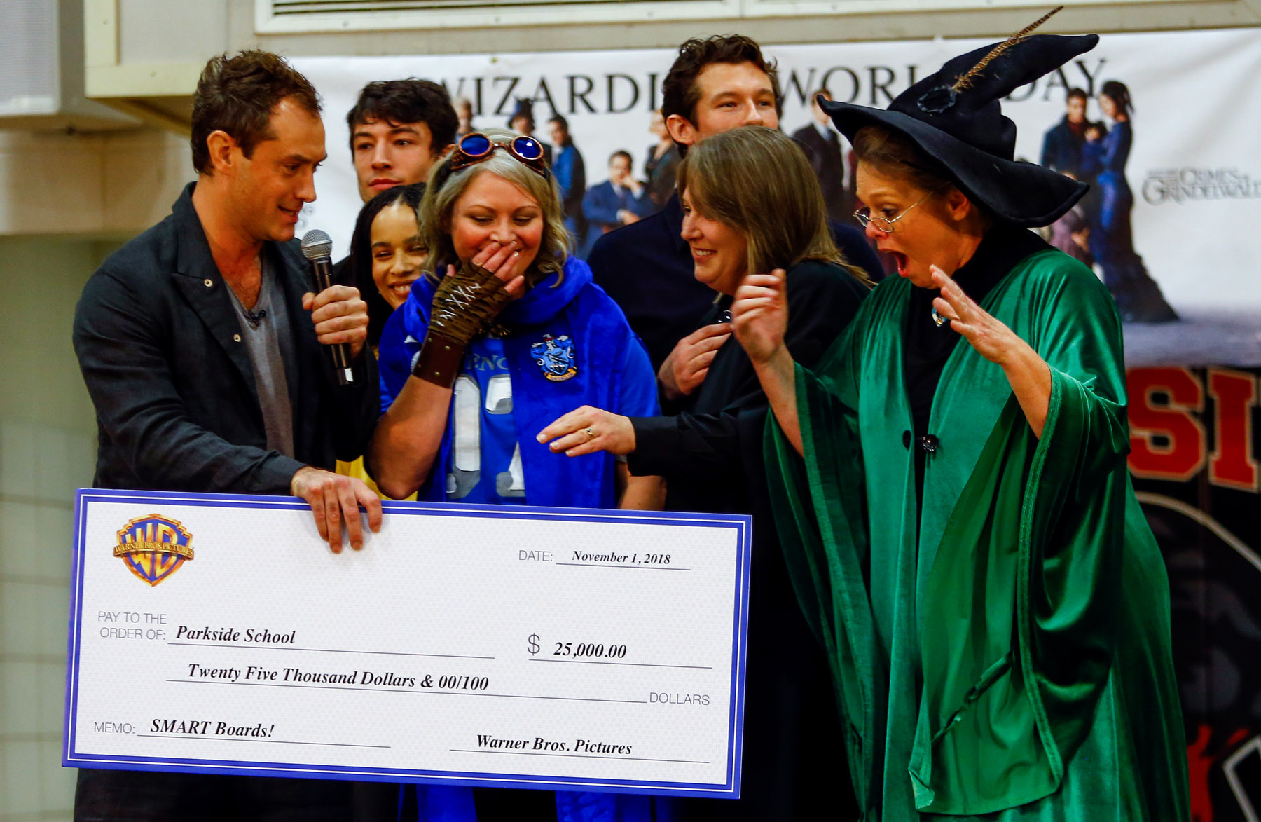 Jude Law from “Fantastic Beasts: The Crimes of Grindelwald” presents a check to teachers Jacy Douglas, Tracey Jones, and Karen Moon to help celebrate Wizarding World Day at Parkside Middle School in Baileyton, AL.  (Photo by Butch Dill/Getty Images)