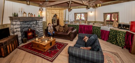 The interior of North Shire's Hagrid's Hut, a room with a cabin feel, soft sofa and armchair by the fire in a circular stone and wood room. It doesn't look as shabby as Hagrid's actual hut but it seems super cosy.