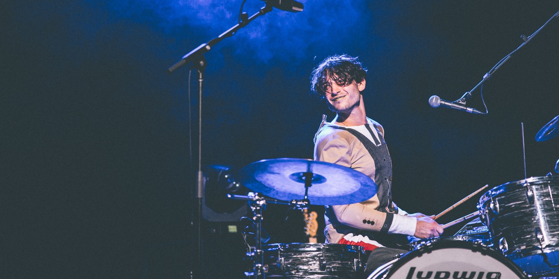 Ezra Miller smiles from behind his drumset during a Sons of an Illustrious Father gig in Singapore.