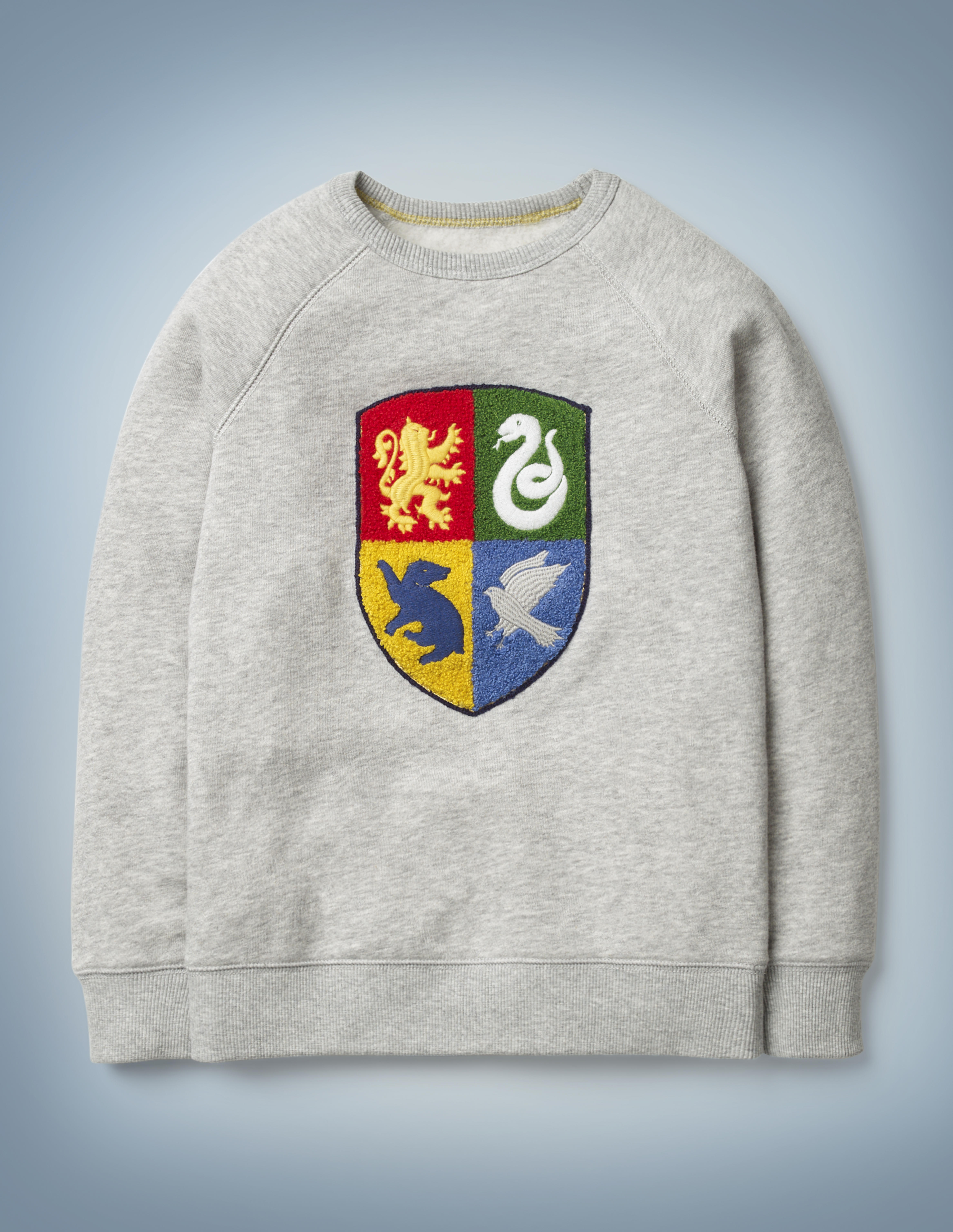 The Mini Boden Hogwarts Crest Sweatshirt in gray features a textured design showcasing the four Hogwarts House emblems. It retails at £28.