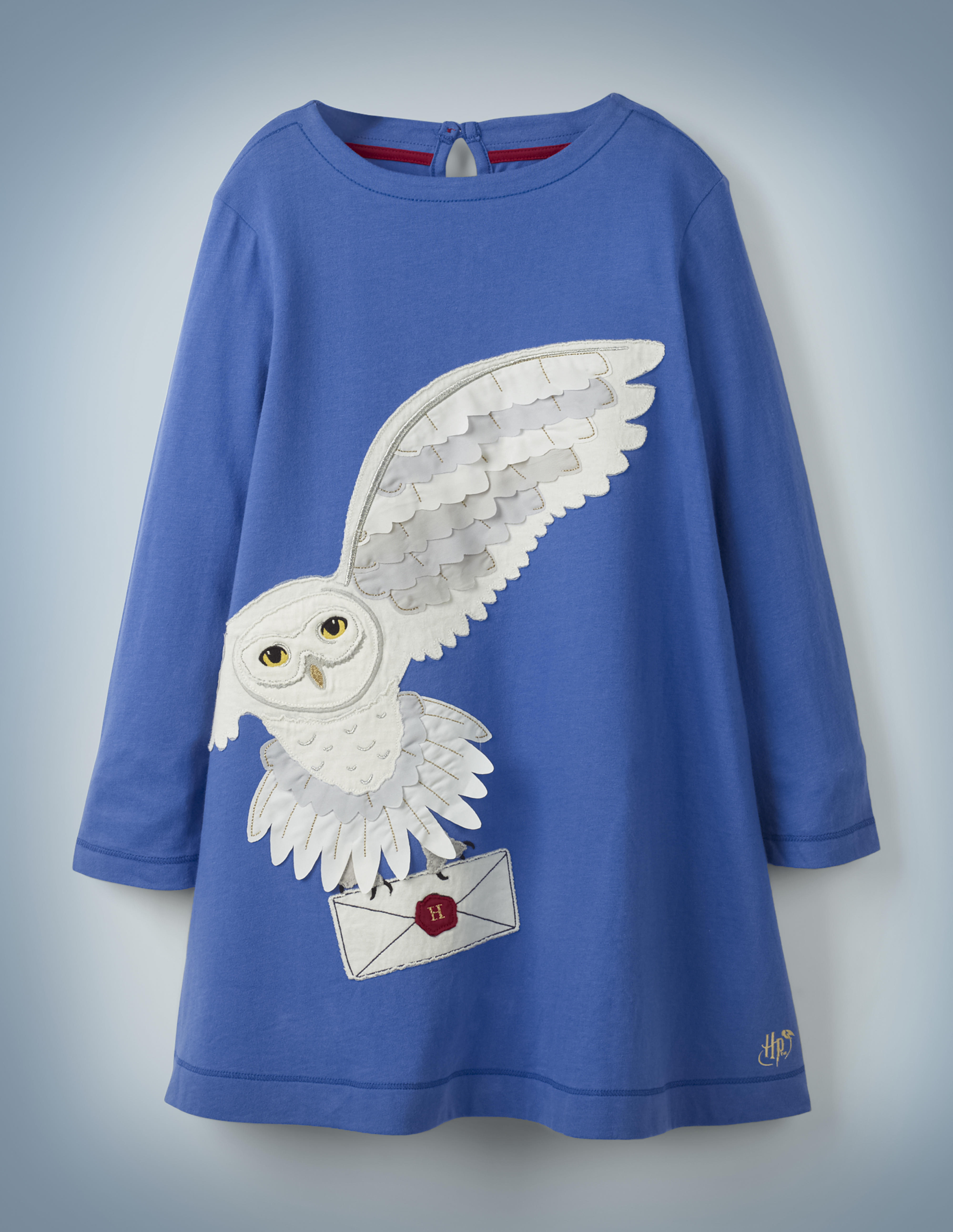 The Mini Boden Hedwig Post Dress in blue features a large, off-center image of Harry Potter’s beloved owl carrying a Hogwarts acceptance letter in her talons. It retails between £28 and £32.