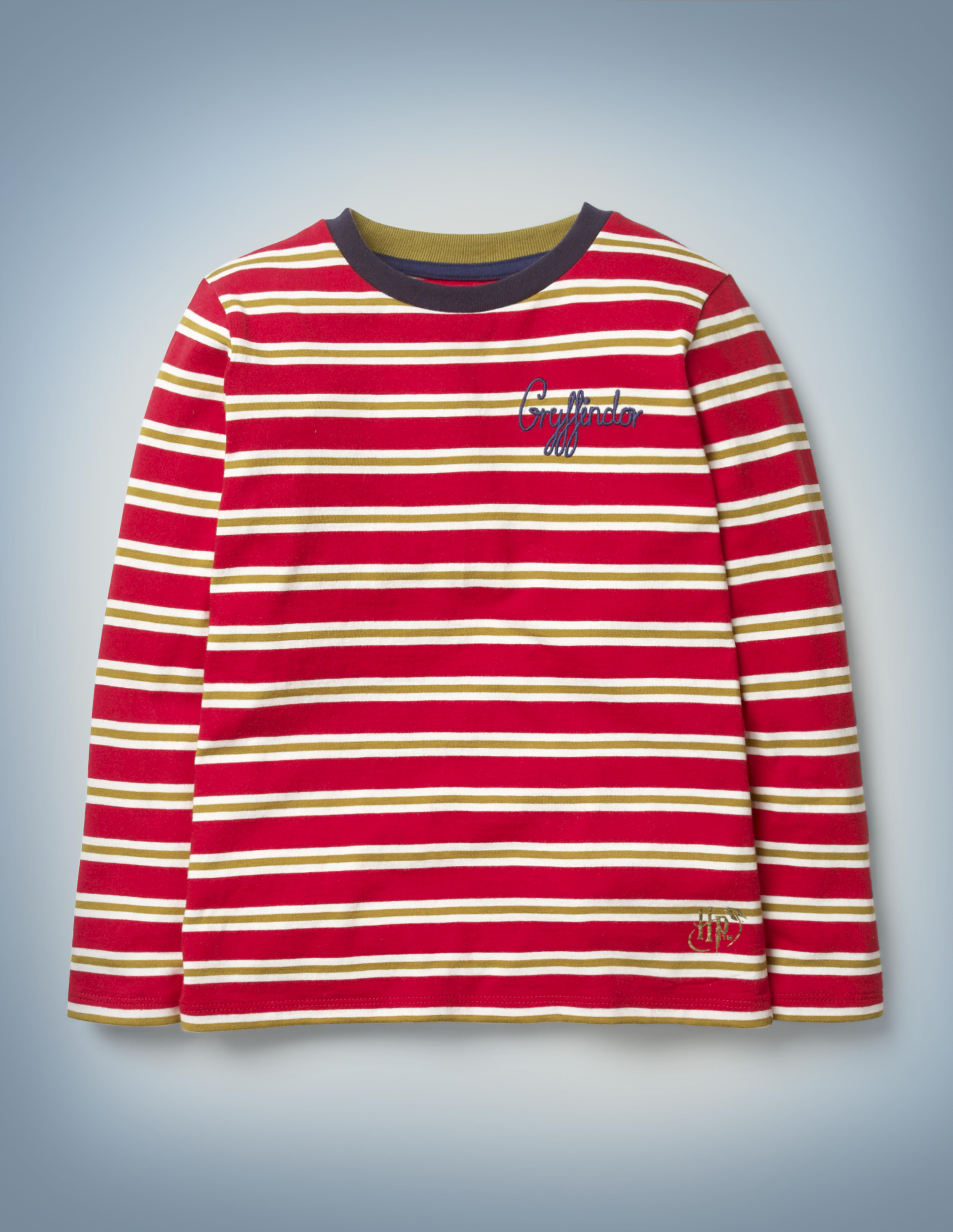 The Mini Boden House Breton in red features all-over red and gold stripes, a blue collar, and “Gryffindor” written in blue script in the front pocket area. It retails between £20 and £22.