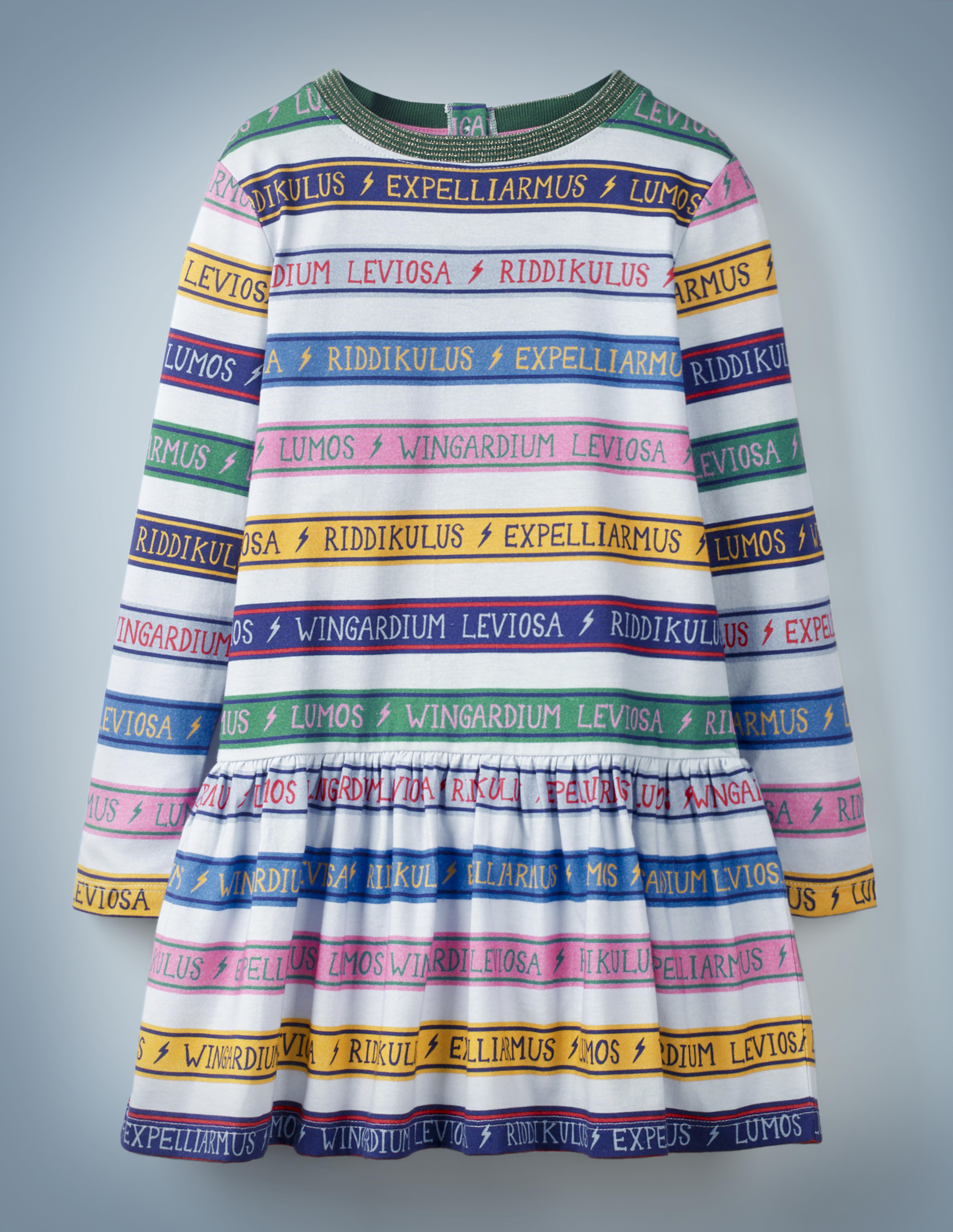The Mini Boden Charms Class Stripe Dress, multi-color, features alternating white and colored stripes. The colored stripes include spell incantations separated by lightning bolts, including “Wingardium Leviosa,” “Riddikulus,” “Expelliarmus,” and “Lumos.” It retails at £28.