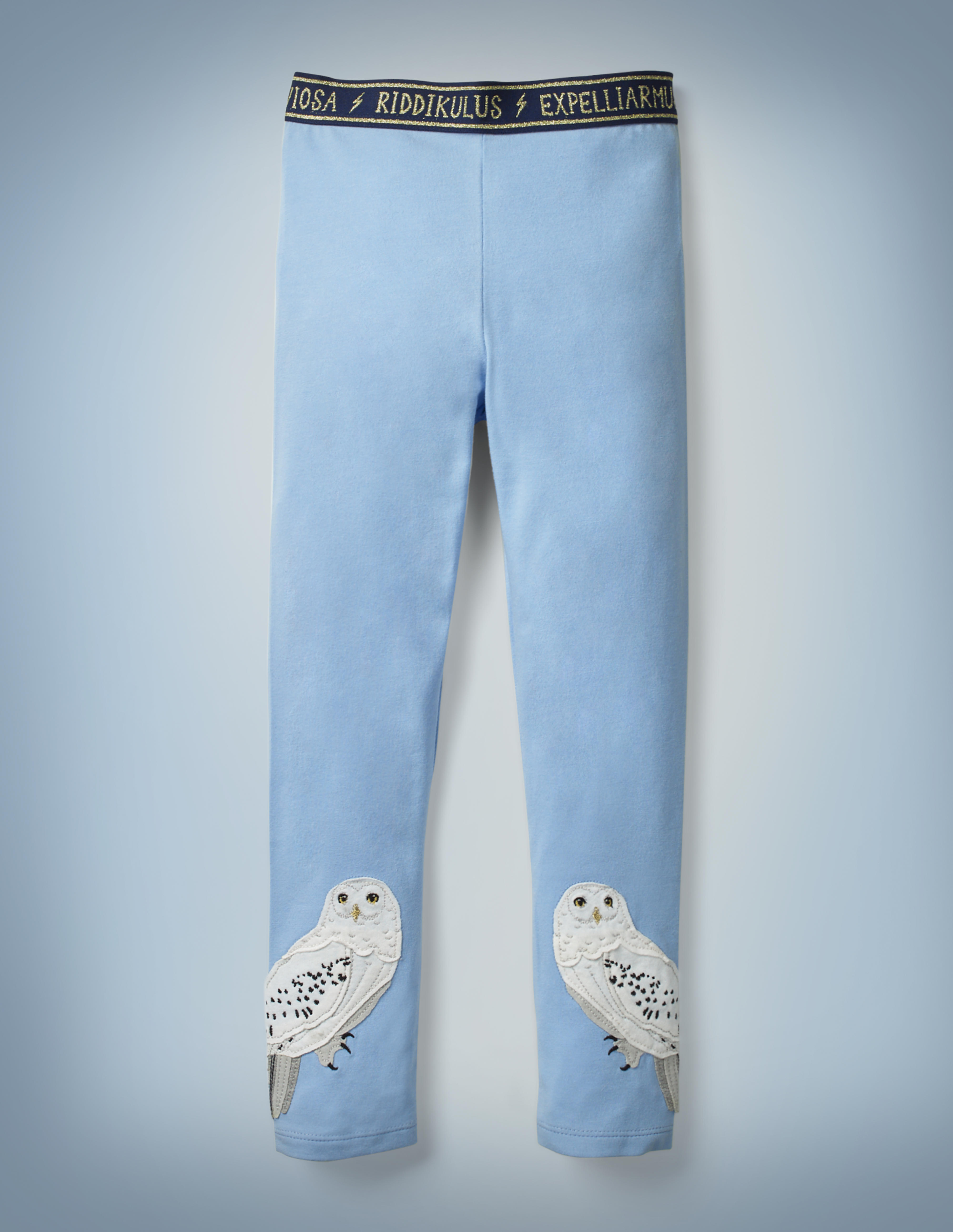 The Mini Boden Hedwig Appliqué Leggings in light blue feature appliqué designs of Hedwig near both cuffs and a navy waistband that features spell incantations such as “Riddikulus” and “Expelliarmus” in gold, separated by lightning bolts. They retail for £18.