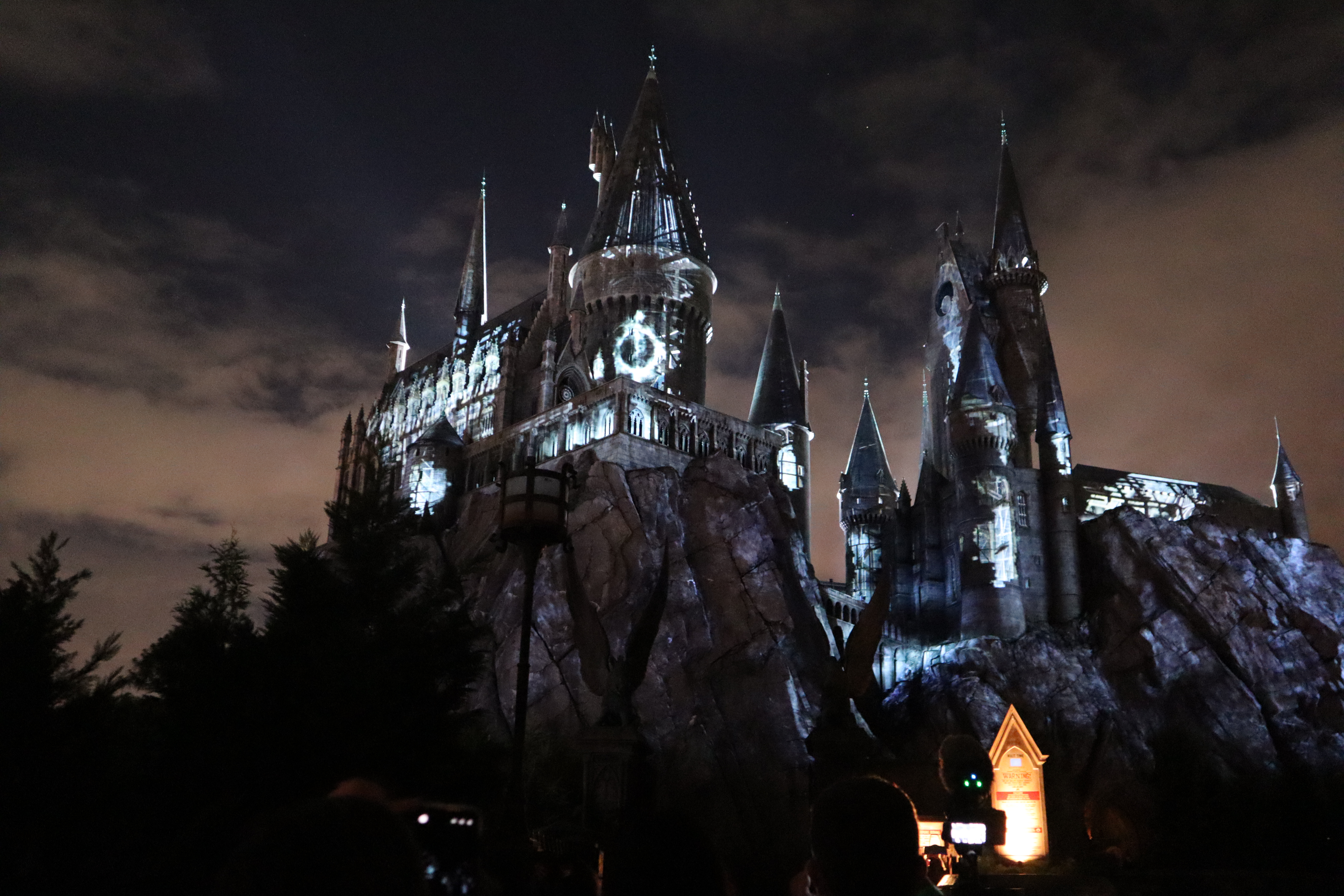 The Deathly Hallows symbol is projected onto the castle.