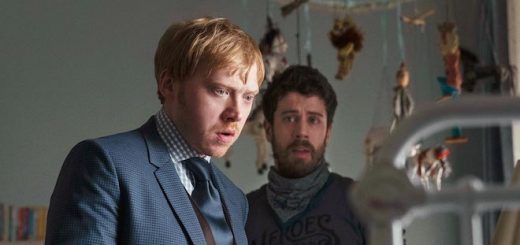 Rupert Grint and Toby Kebbell stare into a baby's crib in a still from the upcoming Apple TV+ series, "Servant".