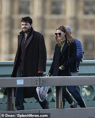 Holliday Grainger as Robin Ellacott and Tom Burke as Cormoran Strike walk along a bridge during filming for “Lethal White” in London.