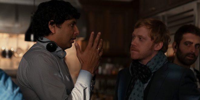 M. Night Shyamalan is directing Rupert Grint on the set of Servant. They are standing in a dark house.