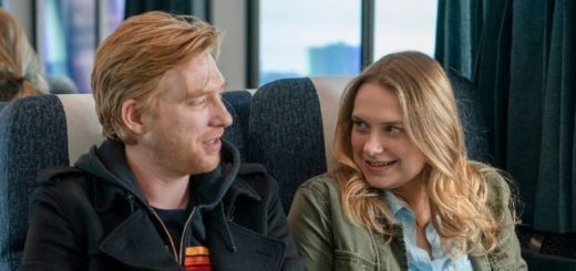 Domnhall Gleeson as Billy and Merritt Wever as Ruby sitting on a train in HBO series Run.