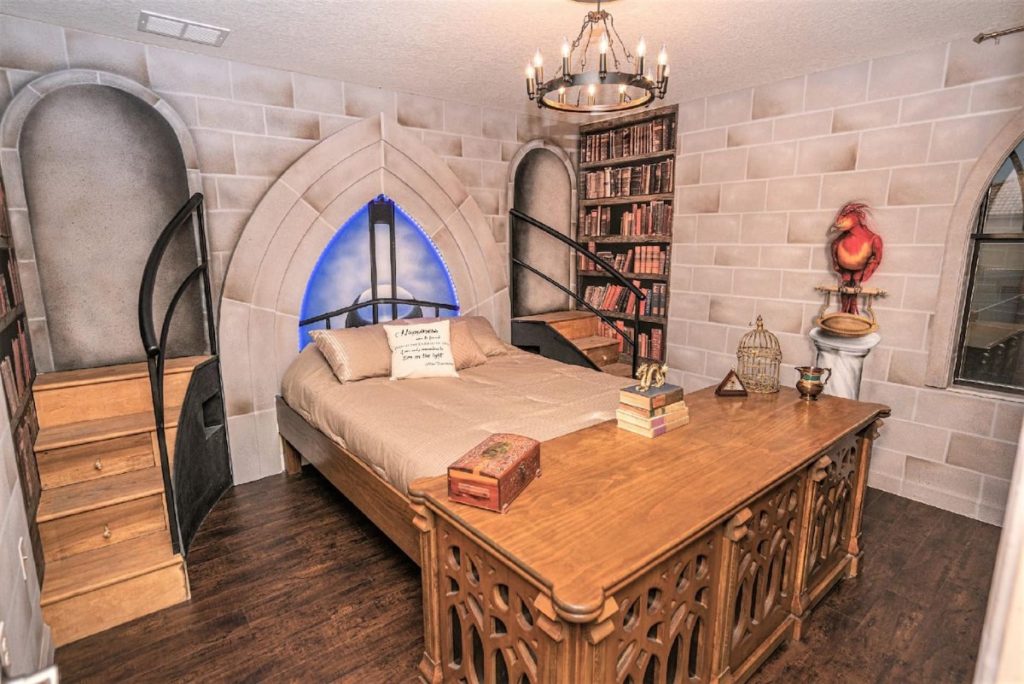 There is a bedroom with wallpaper that resembles a castle's stone walls, and painted bookshelves on each side of the bed. There is also a painting of Fawkes perched on his marble pillar. There are small steps on each side of the bed. At the foot of the bed, there is a huge desk that looks very like Dumbledore's desk.