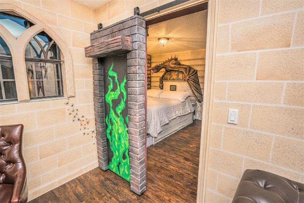 A sliding door with green flames painted on it is open to allow us a view into a bedroom.We can just see the bed in a Diagon Alley-themed bedroom. The headboard is the dome of Gringotts with the escaped and furious dragon perched on top of it, all scupted for real..