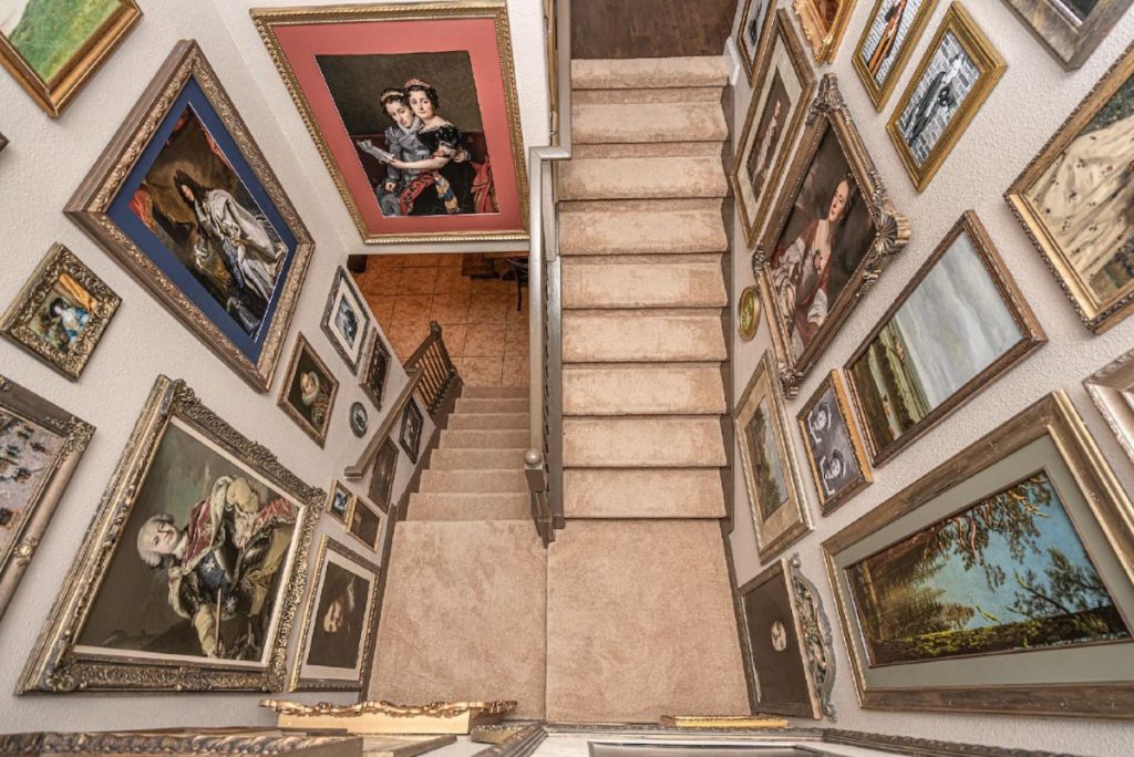 We look down on two fligths of beige stairs. All the walls are covered with paintings of monarchs and others.