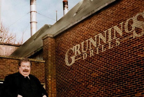 Vernon Dirsley stands next to a brick wall with the Grunnings Drills logo.