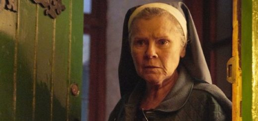 Imelda Staunton stands ominously in a dark doorway dressed as a nun.