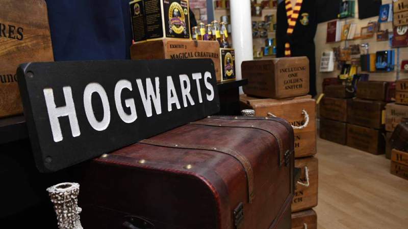 A small Harry Potter shop has a wall full of smaller collectible items, and there are crates and boxes and a Hogwarts sign.