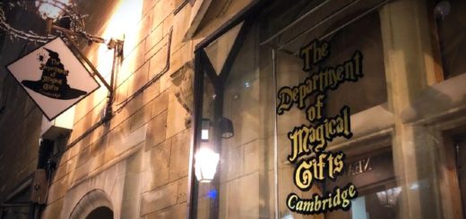 An old stone building has a shopfront for the Department of Magical Gifts, and there is an antique looking shop label and a street light or candelabra.