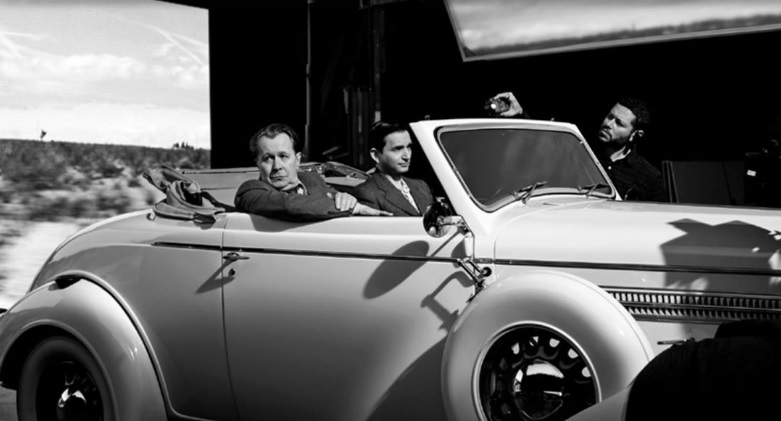 Gary Oldman cruises by in a luxury automobile in a film still from "Mank".