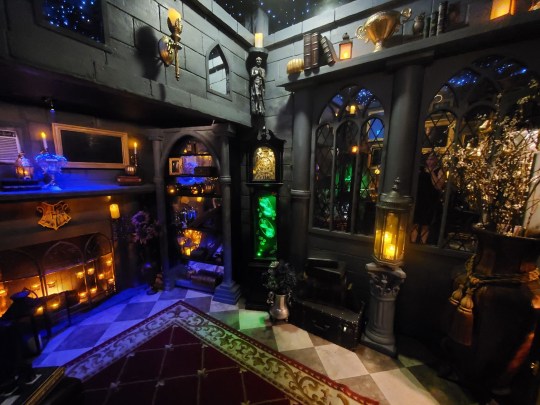 A dark and richly decorated Hogwarts-inspired room is shown with gothic decorations and colourful lights.