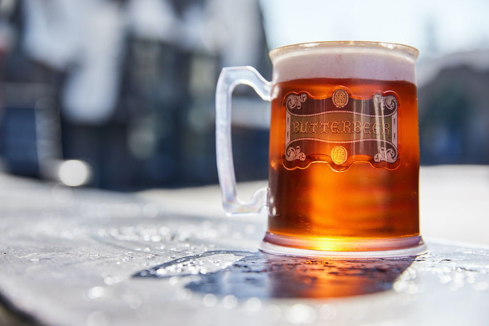 A plastic tankard of butterbeer sits on a wall in the sunshine in Hogsmeade at The Wizarding World of Harry Potter at Universal Studios Hollywood.