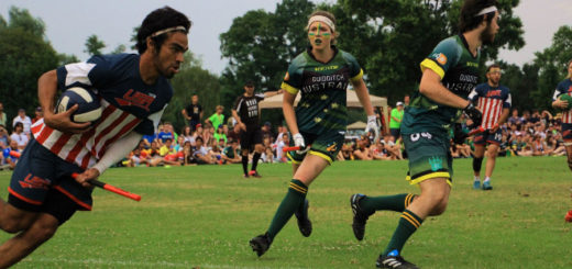 A chaser in an American jersey is shown holding a quaffle and running forward. One chaser in an Australian jersey is running toward them, while another Australian chaser is moving out of view of the camera. Two other American players, referees, and spectators are shown in the background.