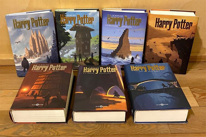 All Harry Potter books are laid out on a table with the new Italian covers that are stylish but evoke the colour and magic of the stories. They have iconic Harry Potter spaces and architecture in their focus.