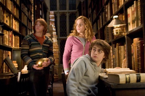Harry, Ron, and Hermione in the library. It's night time and Ron is holding the golden egg from the triwizard tournament