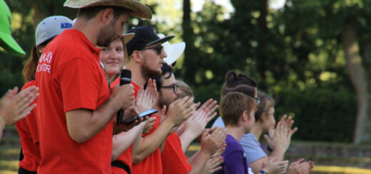 There are eleven people shown standing and clapping. Six of them have red T-shirts.