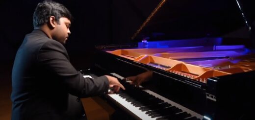 Eshan Denipitiya is sitting at a colorfully lit grand piano, playing.