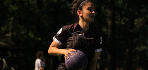 There is a female beater in a dark jersey holding a purple bludger.