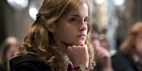 Hermione rests her head on her hand, deep in thought, with a serious expression