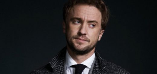 Tom Felton in suit and tie against black background