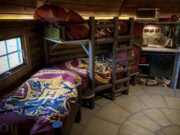 The Hagridd's Hideaway interior resembles the cozy Gryffindor dormitory with maroon Hogwarts crest bedding.