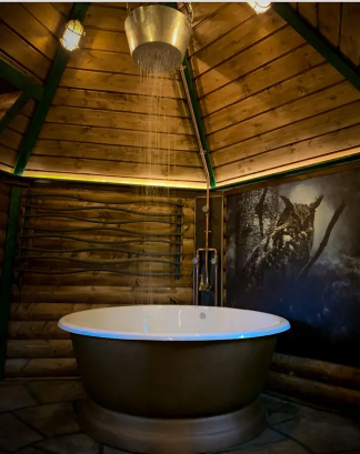 The Hagridd's Hideaway in England has a bathroom with a bowl tub and waterfall shower.