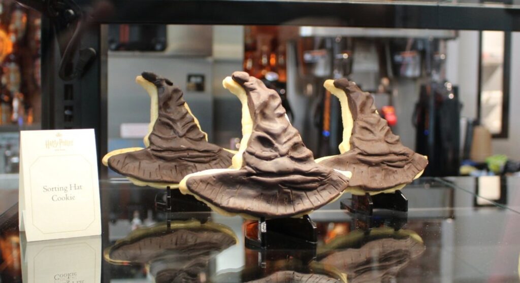 Three chocolate-dipped Sorting Hat cookies are on display in a snack bar.