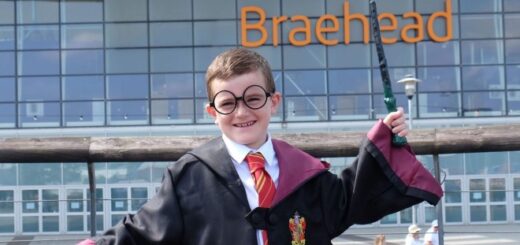 A child in Harry Potter glasses and robes is waving a wand in front of the Braehead shopping mall.